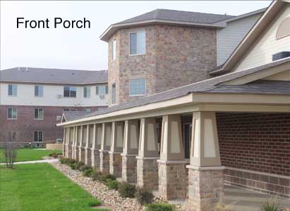 A residential building with a front porch featuring multiple columns and a brick exterior.