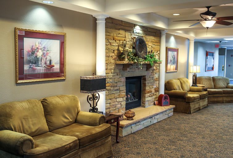 A cozy living room featuring a stone fireplace, comfortable couches, and decorative art pieces.