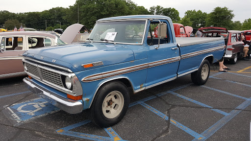 A classic blue Ford pickup truck from the 1970s, showcased at a car event.