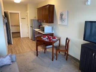 A cozy apartment kitchen with a small dining table and chairs, complete with a fridge and microwave.