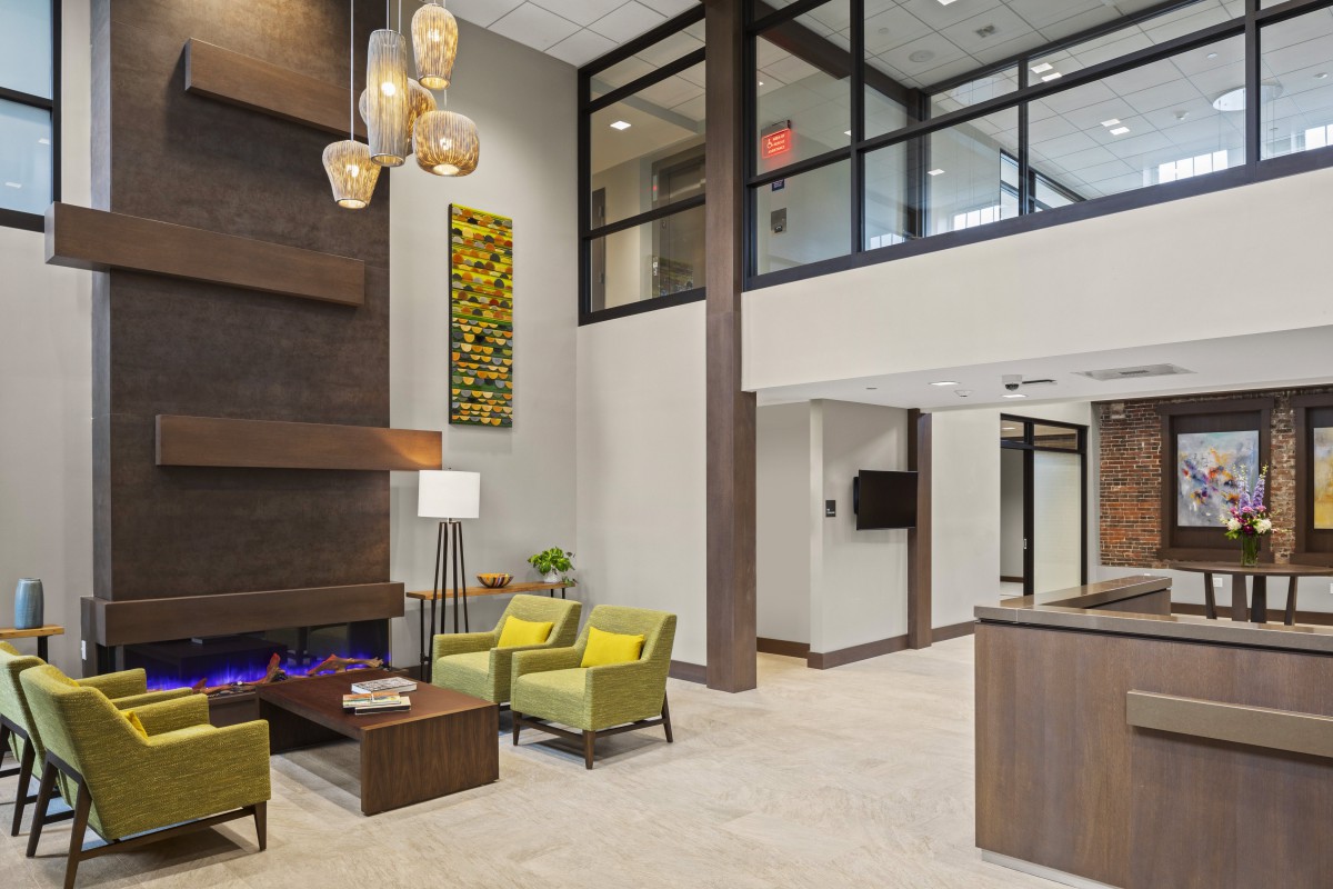 A modern lobby with stylish furnishings, featuring a seating area and a decorative fireplace.