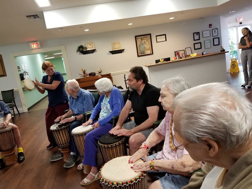 A group of people participating in a drumming session at a community center.