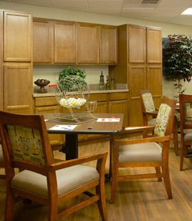 A cozy kitchen area with wooden cabinets, a dining table, and upholstered chairs.