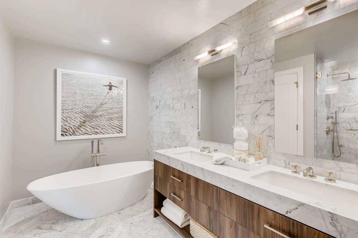 A modern bathroom featuring a freestanding bathtub, spacious double sink vanity with mirrors, and elegant marble accents.