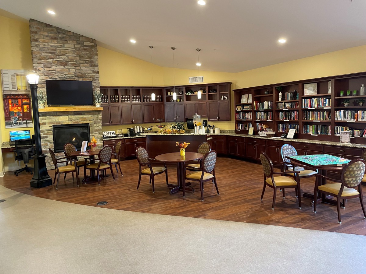 A cozy library with bookshelves, a fireplace, and seating area.