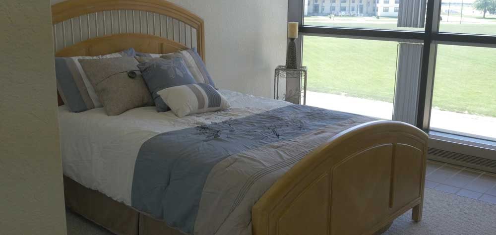 A cozy bedroom with a neatly made bed and large window allowing natural light.