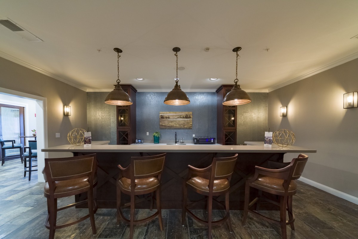 A cozy bar interior featuring a countertop with bar stools and pendant lighting.
