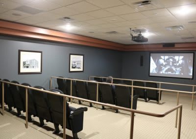An empty theater room with seating facing a movie screen.