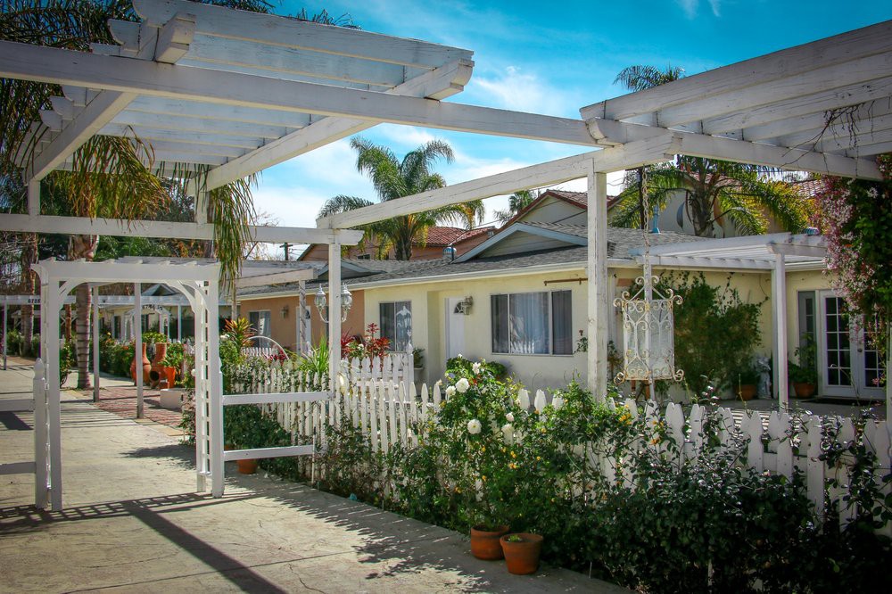 A charming residential area with houses, a white picket fence, and vibrant gardens.