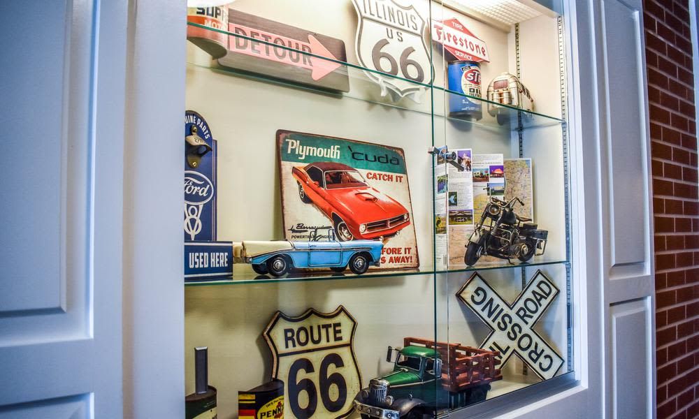 A collection of Route 66 memorabilia and vintage items displayed in a glass case, featuring toy cars and retro signs.