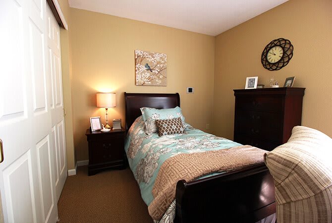 A cozy bedroom with a single bed, nightstand, and warm lighting.