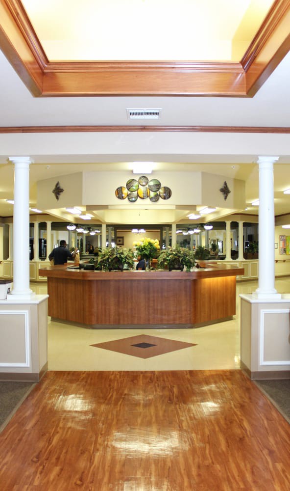 A well-lit reception desk area with plants and decorative columns.