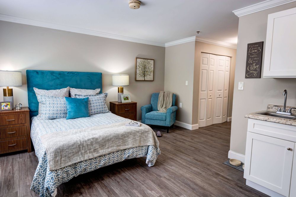 A modern bedroom featuring a comfortable bed with blue accents, a cozy armchair, and stylish decor.