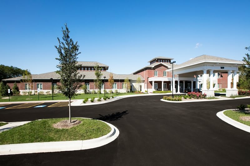 A modern building with a landscaped entrance and spacious parking lot.