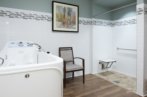 A modern bathroom featuring a comfortable chair, elegant artwork, and an accessible bathtub.