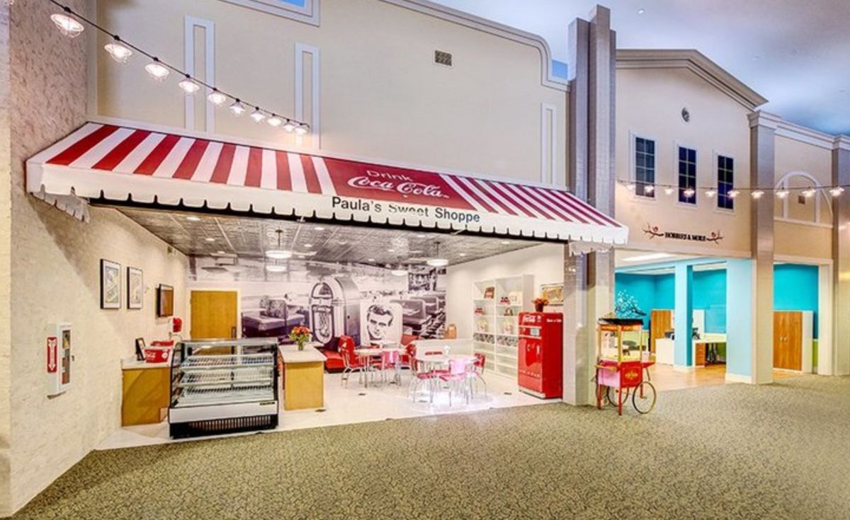 A retro-themed cafe with a red and white striped awning, featuring vintage decor and furnishings.