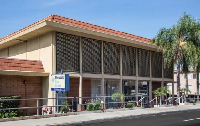 Street view of a motel building with large windows and a sign.