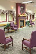 A cozy living room with purple chairs and a fireplace.