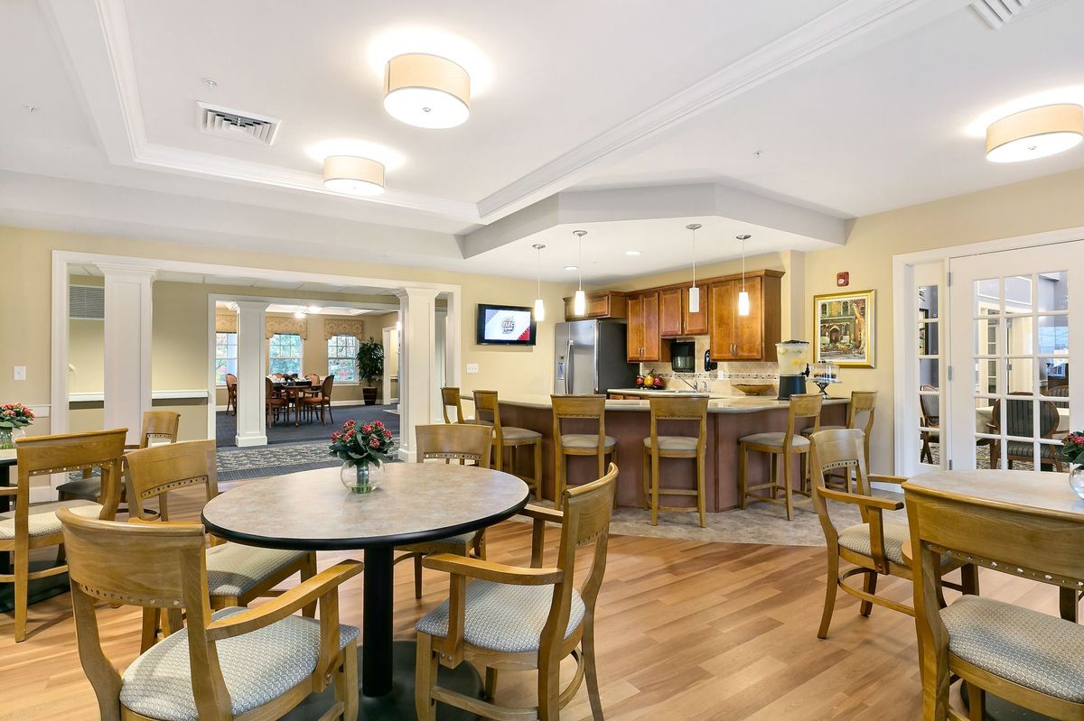A cozy dining area with a kitchen setup, featuring wooden flooring and comfortable seating.