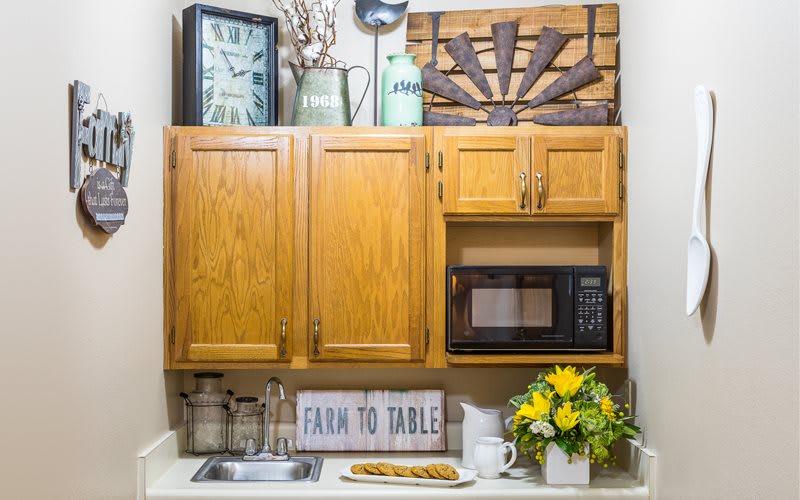 A cozy kitchen corner featuring wooden cabinets, a microwave, and farmhouse-style decor.