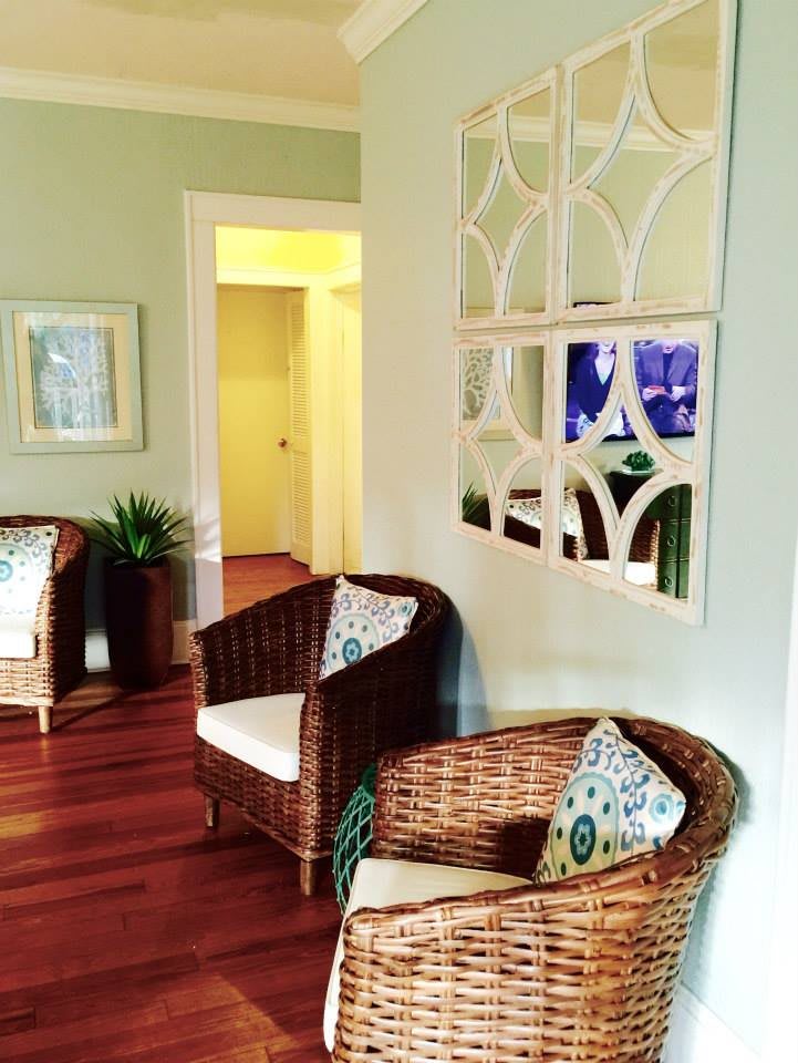 A cozy living room with wicker chairs, mirror decor, and hardwood floors.