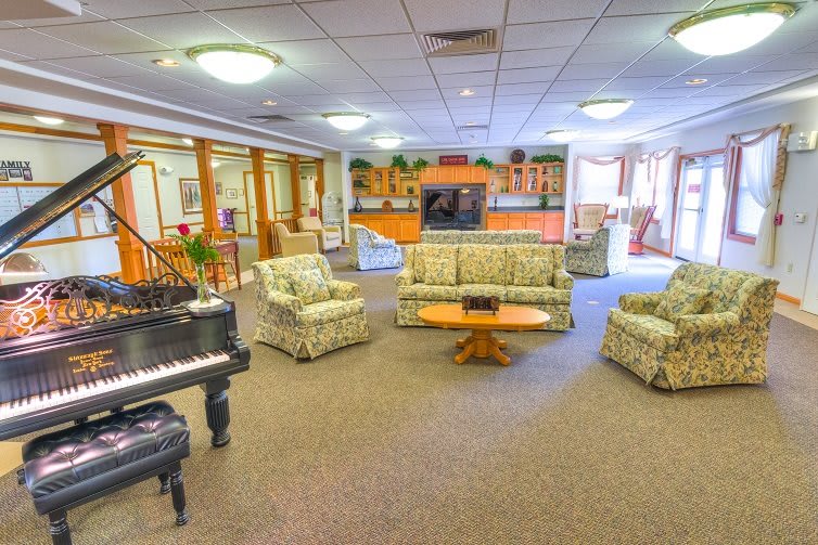 A spacious living room with a piano and comfortable seating.