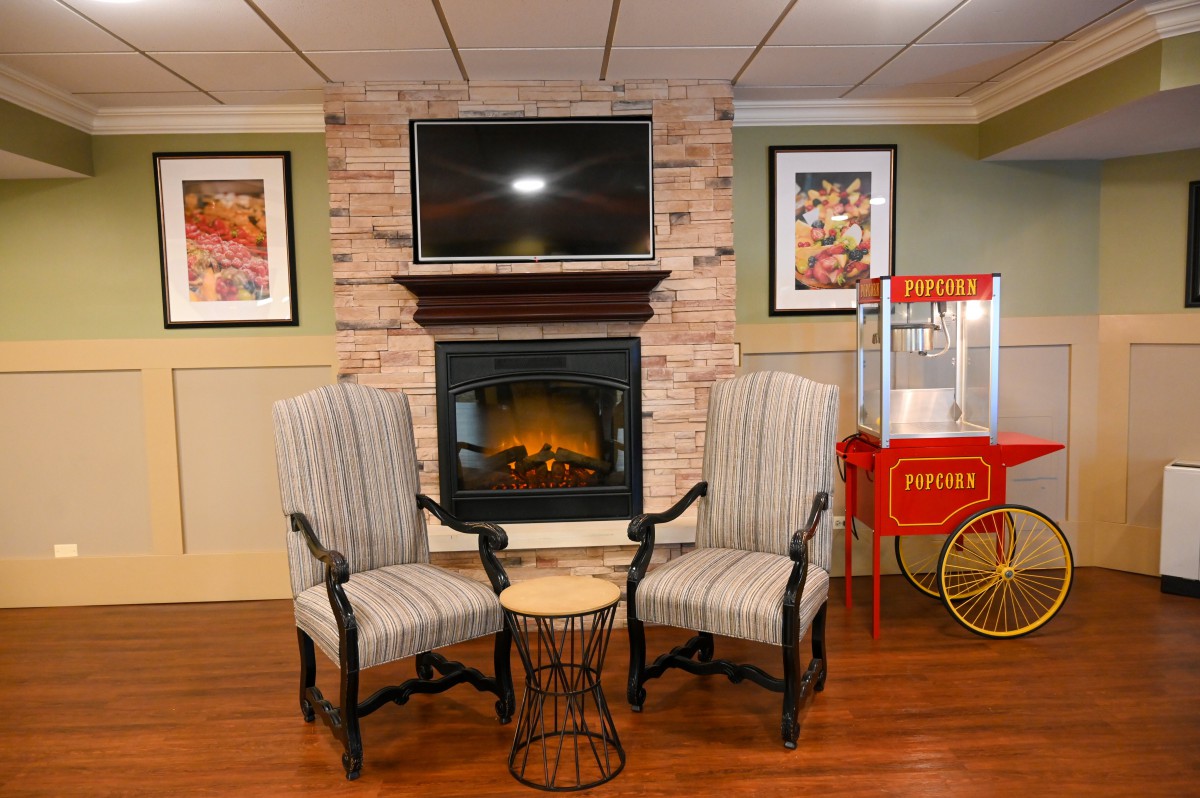 A cozy living room interior featuring a fireplace, two striped chairs, and a popcorn machine.