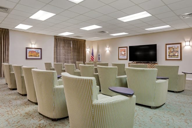 A modern meeting room with comfortable chairs arranged in front of a large television.