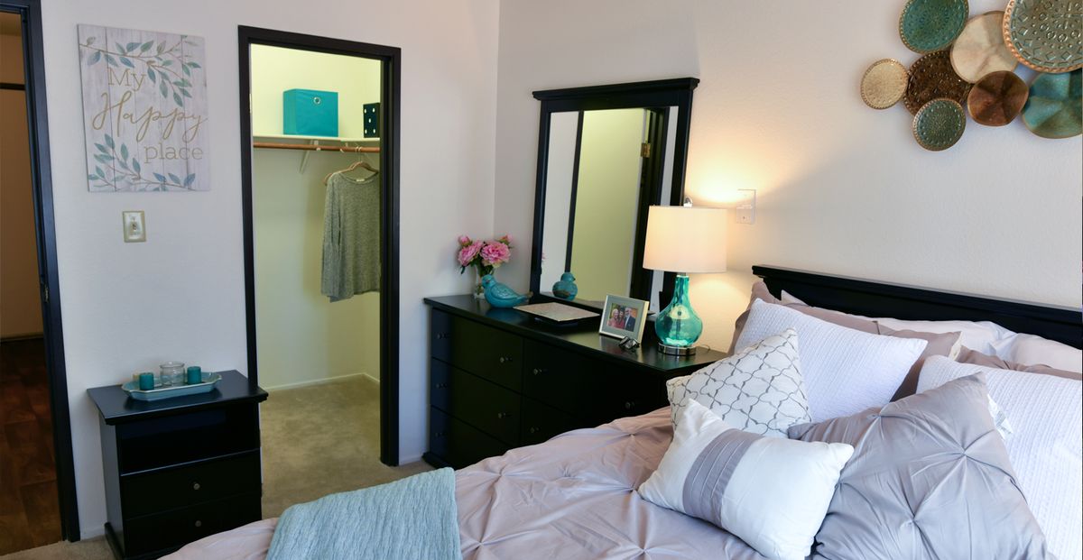 A cozy bedroom with a bed, dresser, and open closet.