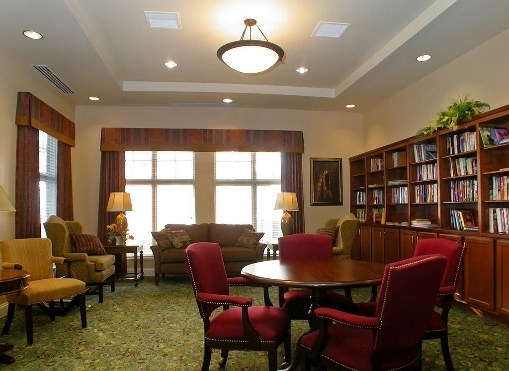 A cozy living room with a library area, featuring comfortable seating and warm lighting.