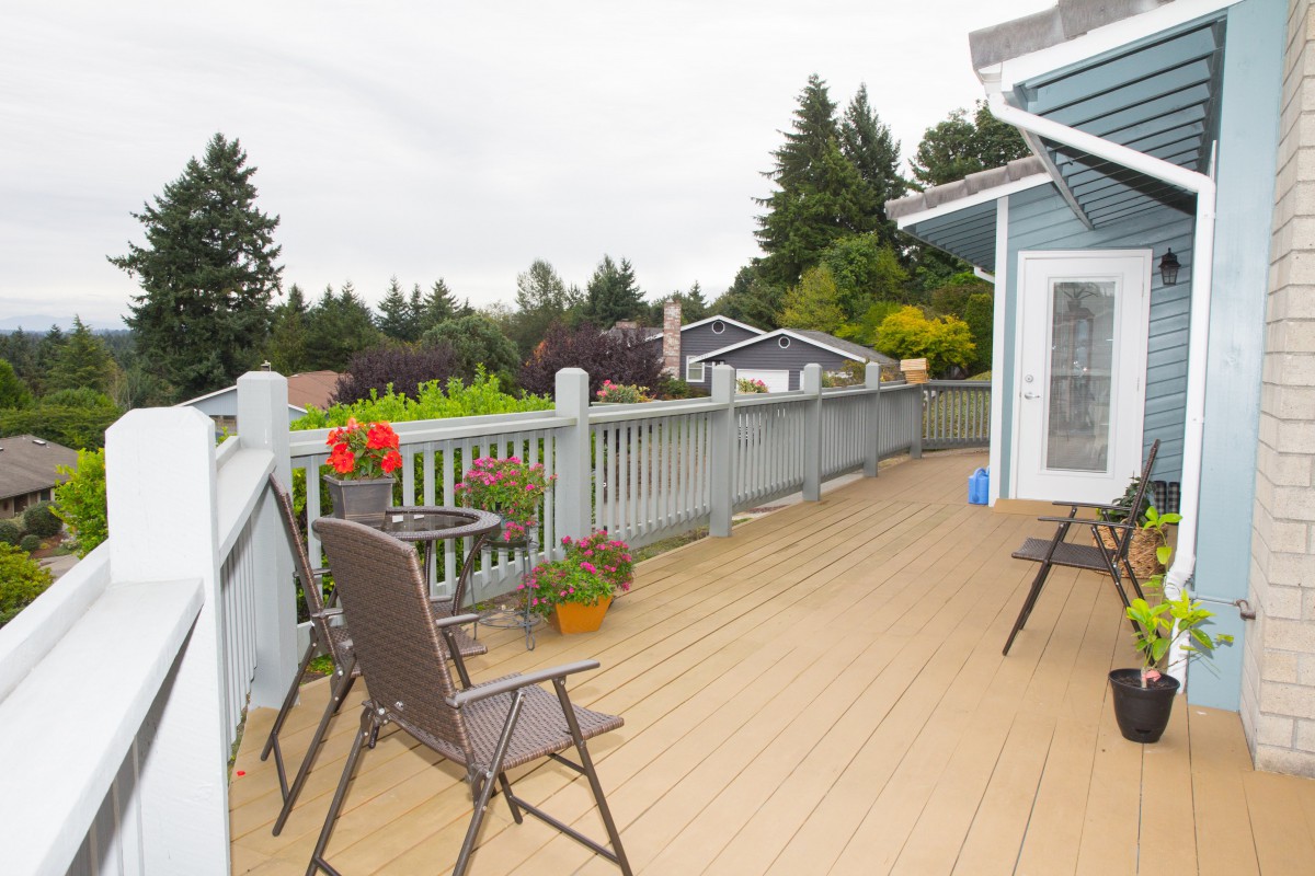 A spacious outdoor deck with chairs and plants, surrounded by trees.