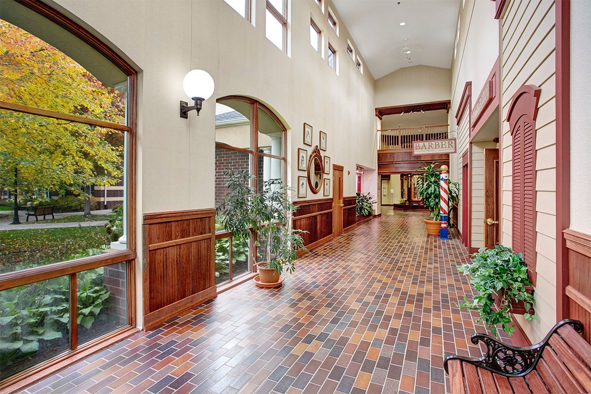 A spacious hallway with a brick floor, adorned with plants and decorative elements.