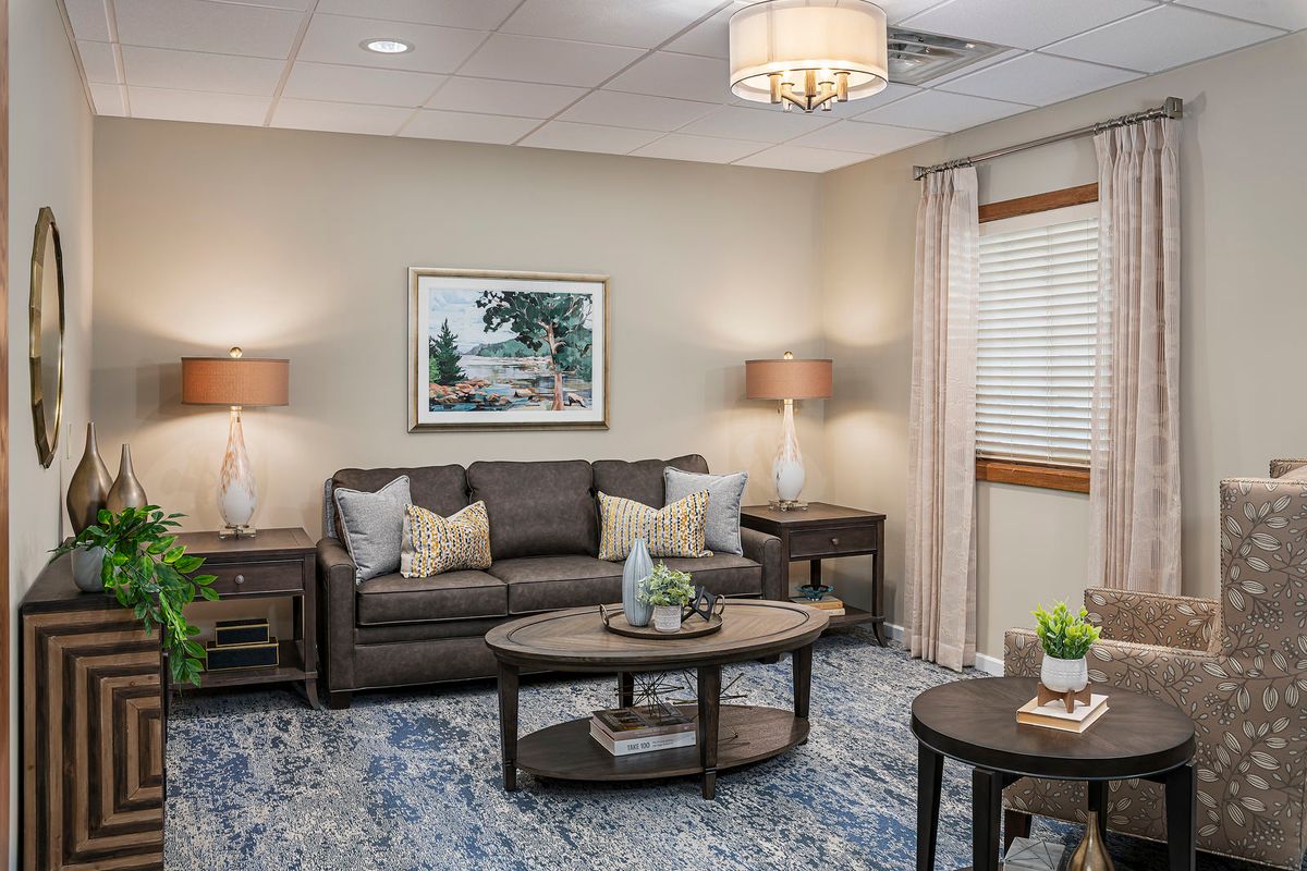 A cozy living room with neutral tones, featuring a sofa, coffee table, and lamps.