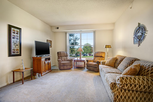 A cozy living room featuring a comfortable sofa, relaxing chairs, and ample natural light from the window.