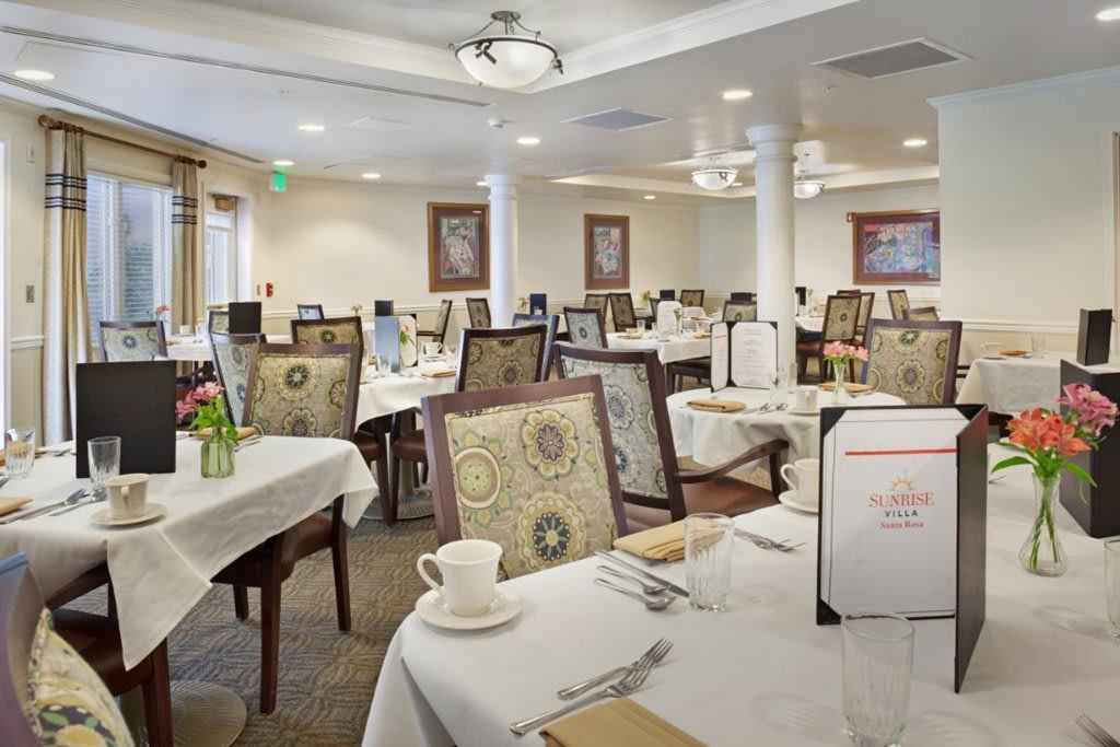An elegantly set dining room with multiple tables and chairs ready for guests.