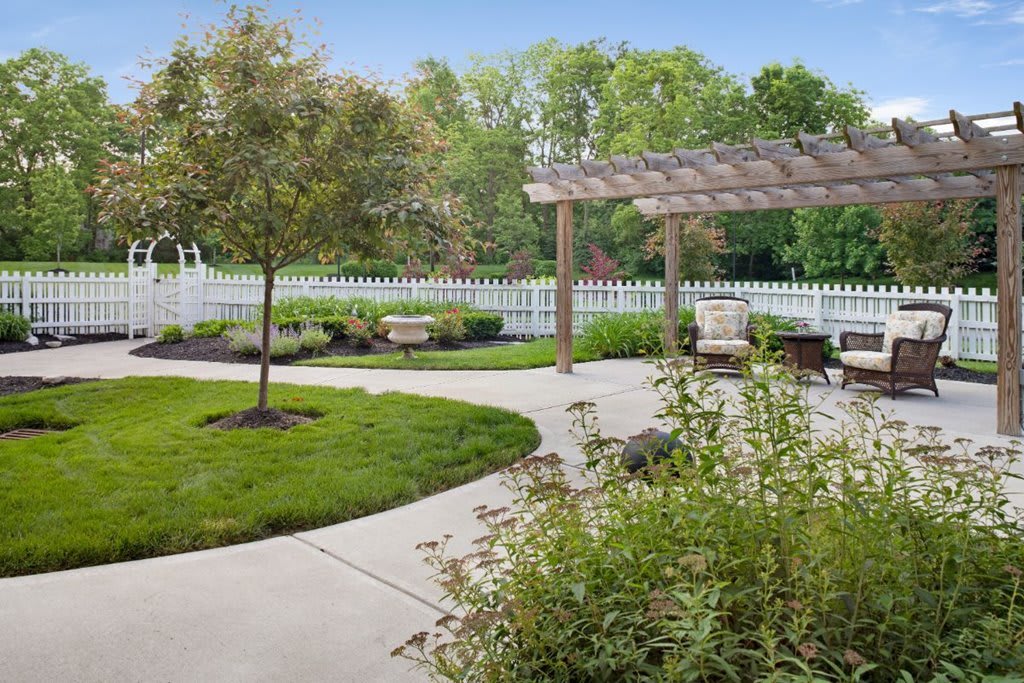 A serene backyard garden with a pergola and outdoor seating area surrounded by greenery.