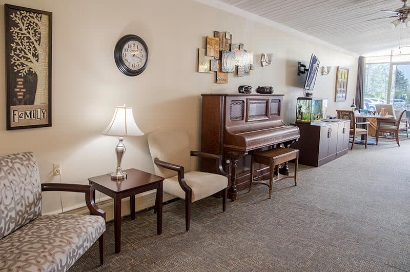 A cozy living room featuring a piano, comfortable chairs, and tasteful decor.