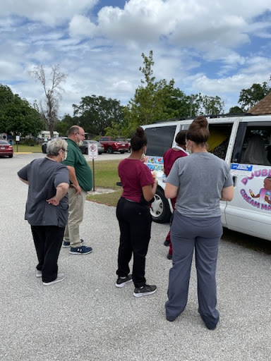 A group of people gathered around a van, likely engaging in a community event or activity.