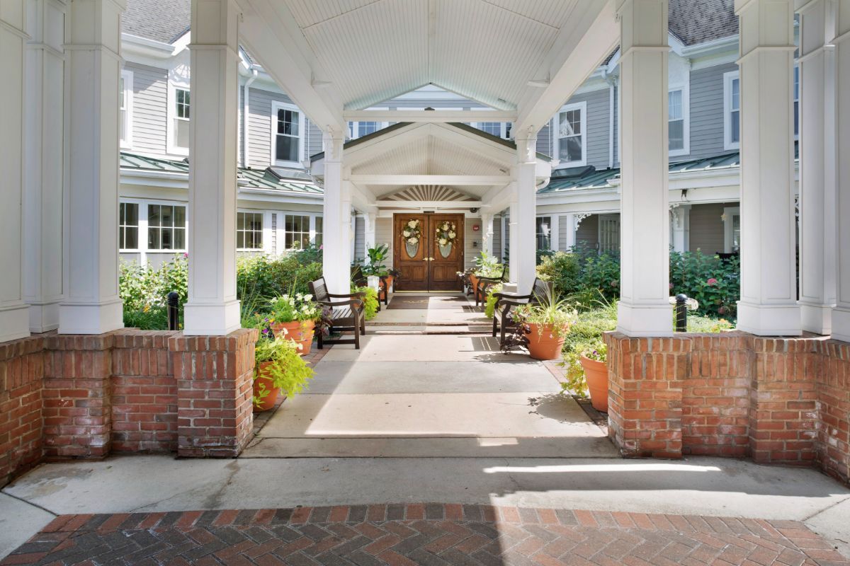 A welcoming entrance with columns and potted plants leading to a building.