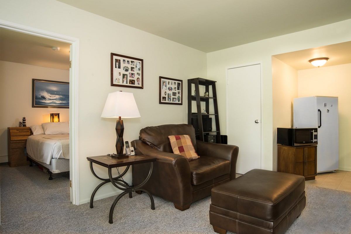A cozy living room featuring a leather armchair, ottoman, and a decorative table lamp.