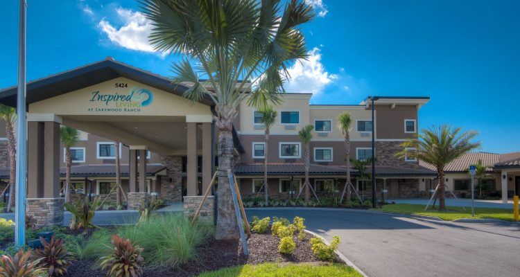 A modern hotel exterior with palm trees and landscaped entrance.