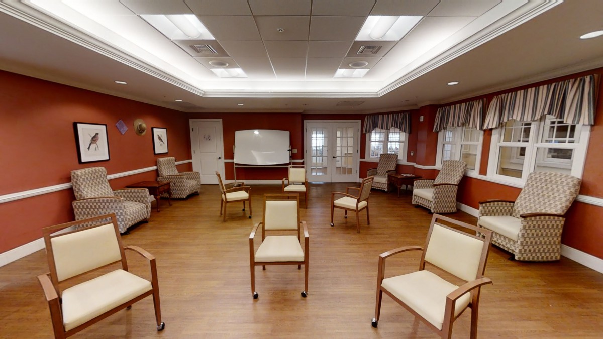 An empty meeting room with arranged chairs and a wooden floor.
