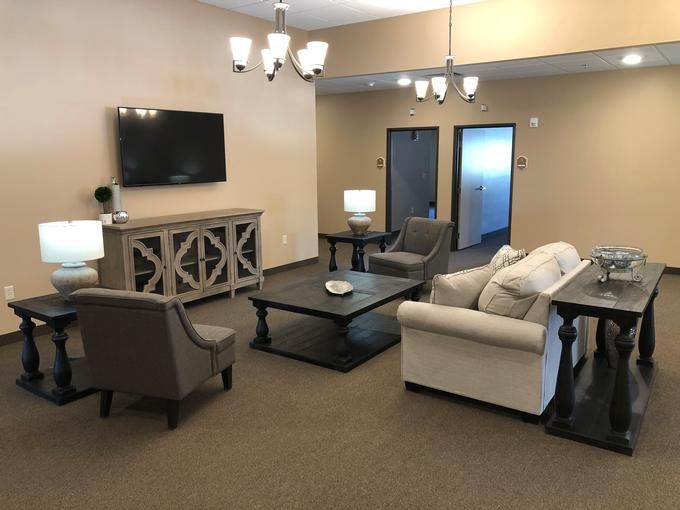 A cozy living room with a sofa, armchairs, a coffee table, and a television.