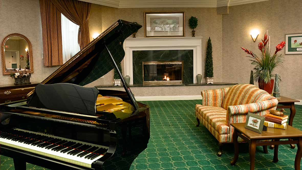 A cozy living room featuring a grand piano and a fireplace.