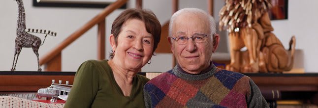 An elderly couple smiling together indoors.