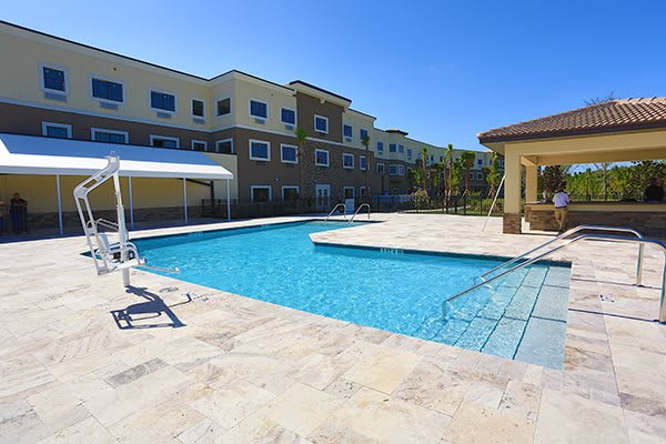 A sunny day at a residential apartment complex featuring an outdoor swimming pool.