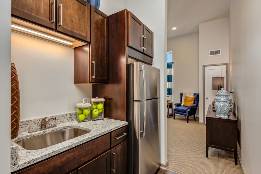 A modern apartment kitchen with dark wood cabinets and stainless steel appliances.
