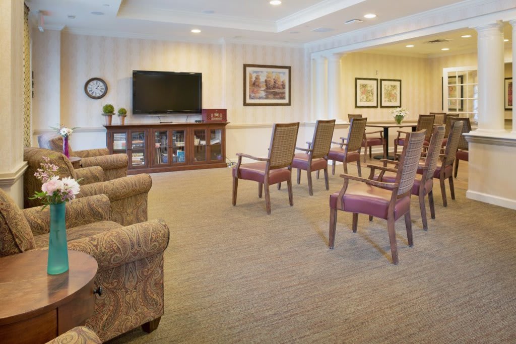 A well-arranged living room with multiple chairs facing a television.