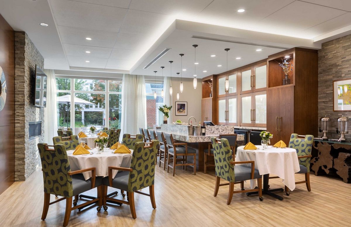 An elegant restaurant dining area with neatly arranged tables and chairs, illuminated by warm lighting.