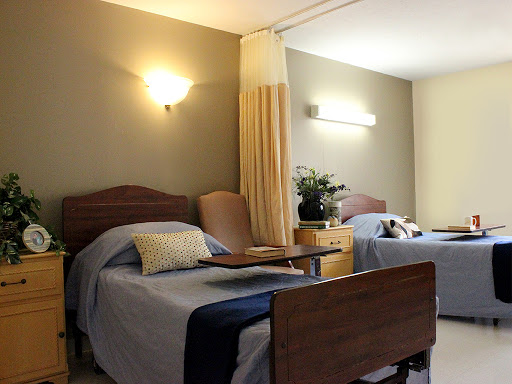 A comfortable and well-lit hospital room featuring two beds with cozy bedding.